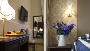 Une chambre d’hôtel équipée d’un bureau, d’une lampe, d’un miroir, d’un vase avec des fleurs et d’un lit avec une literie à rayures.