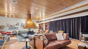 A spacious living room with a wooden ceiling, leather sofas, a coffee table, and a fireplace.