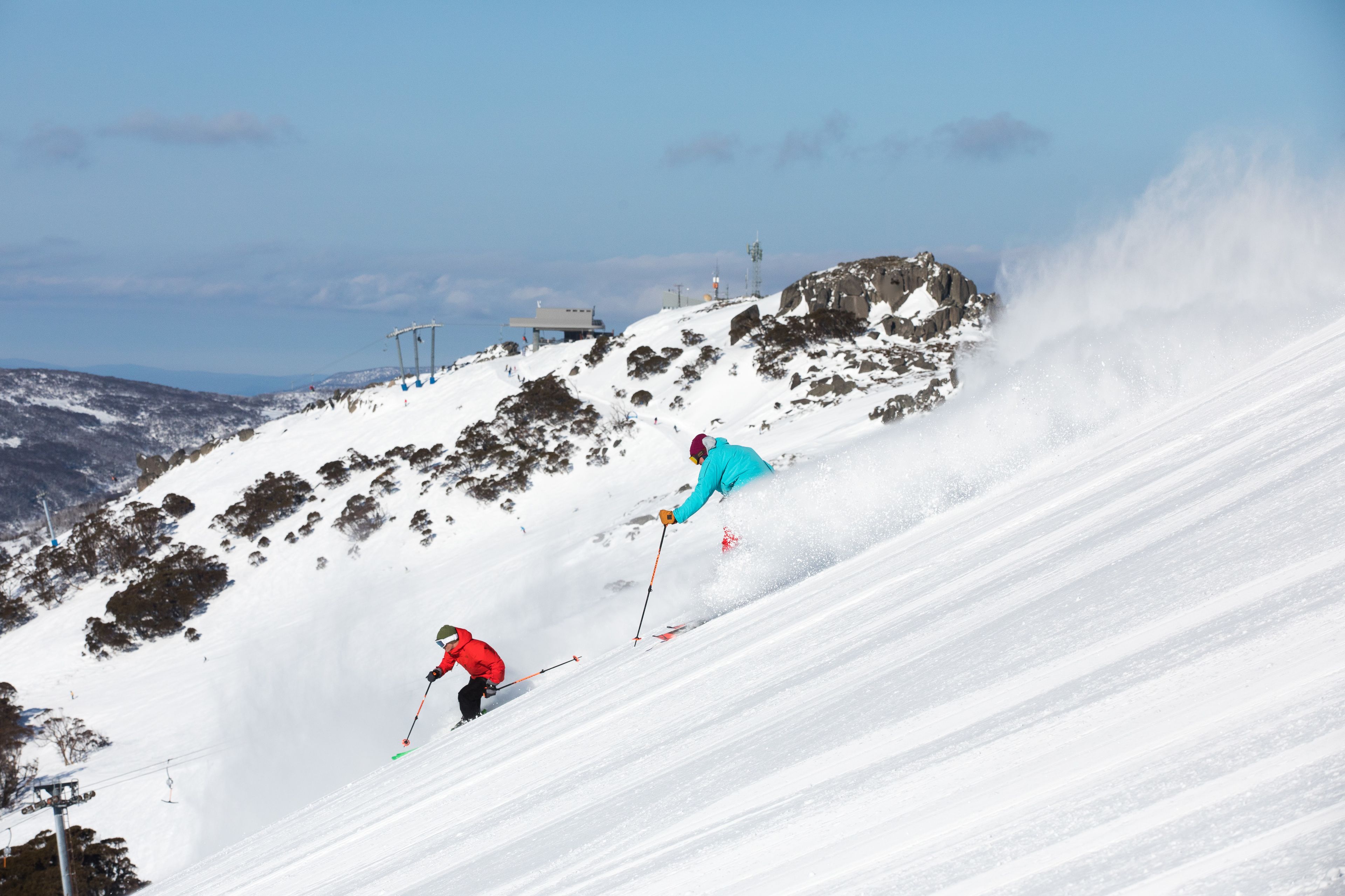 A snowy ski slope with skiers descending.
