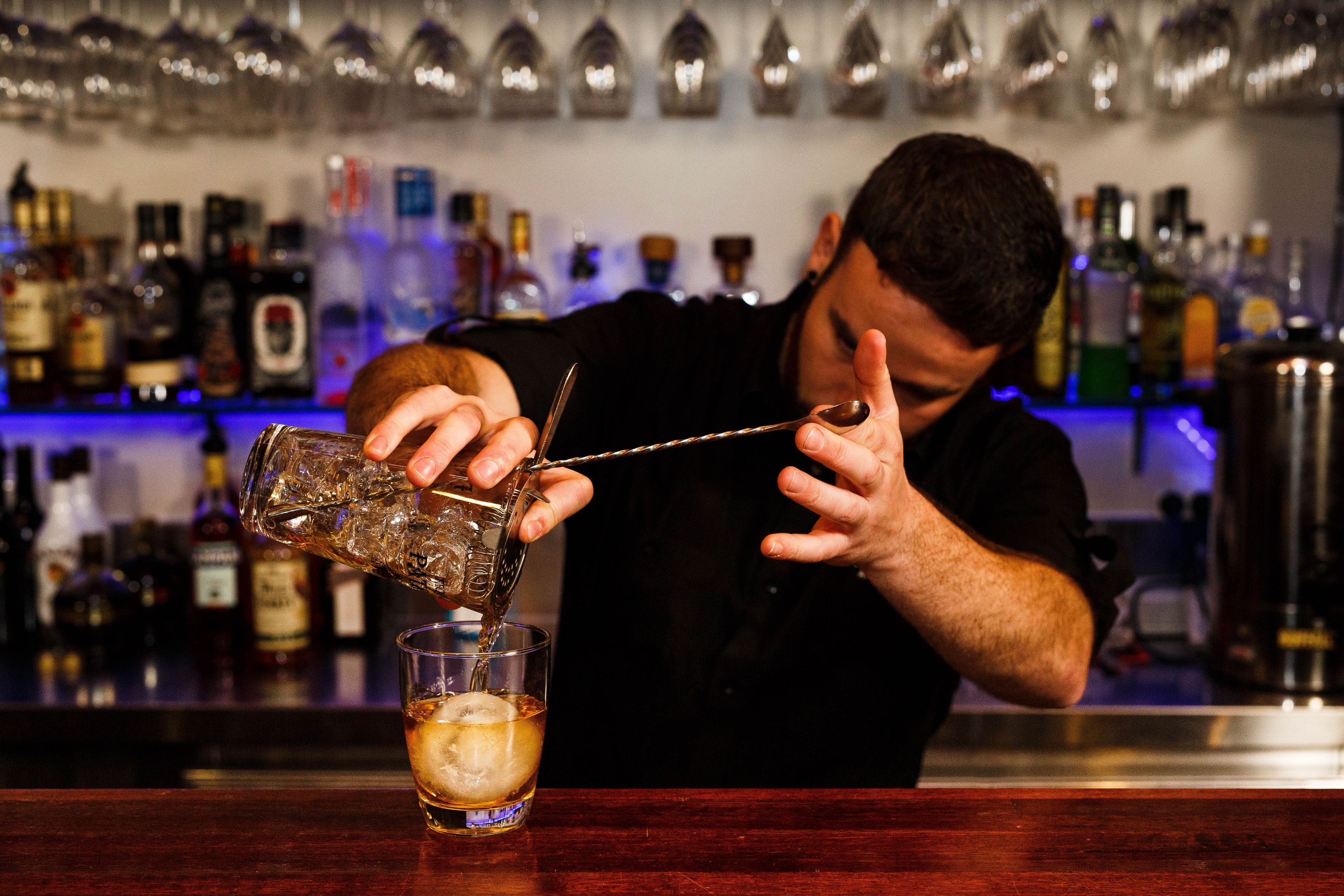 Een barman schenkt een drankje in.