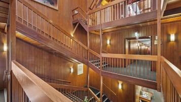A multi-level wooden interior with a staircase, wooden railings, and a Christmas tree.