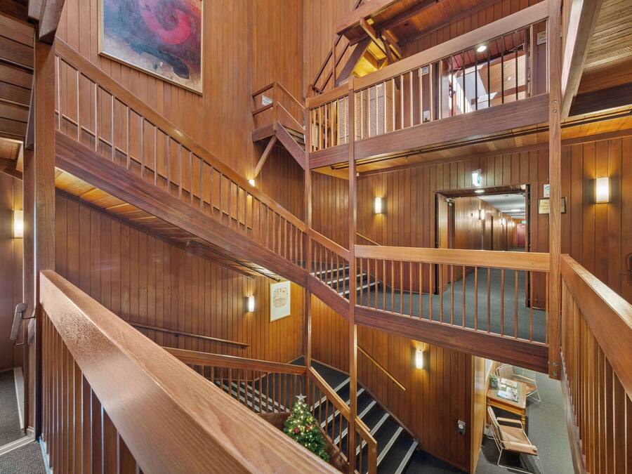A multi-level wooden interior with a staircase, wooden railings, and a Christmas tree.