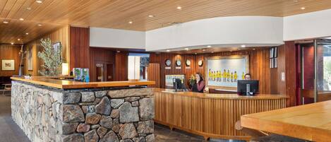 A reception area with a stone counter, wooden panel walls, and a checkered floor.