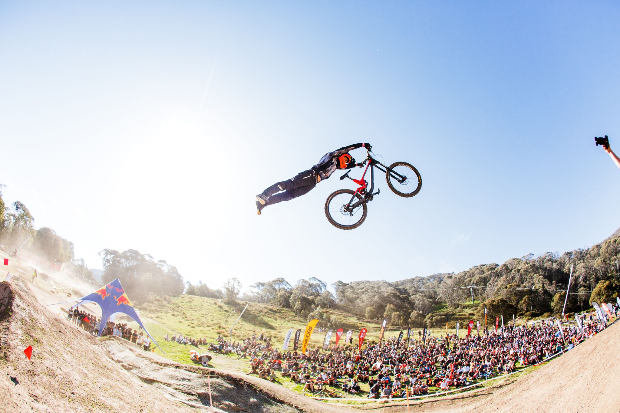 A BMX rider performing a jump over a crowd at a motocross event.