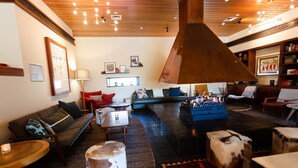 A modern living room with a large fireplace, comfortable seating, and a wooden ceiling.