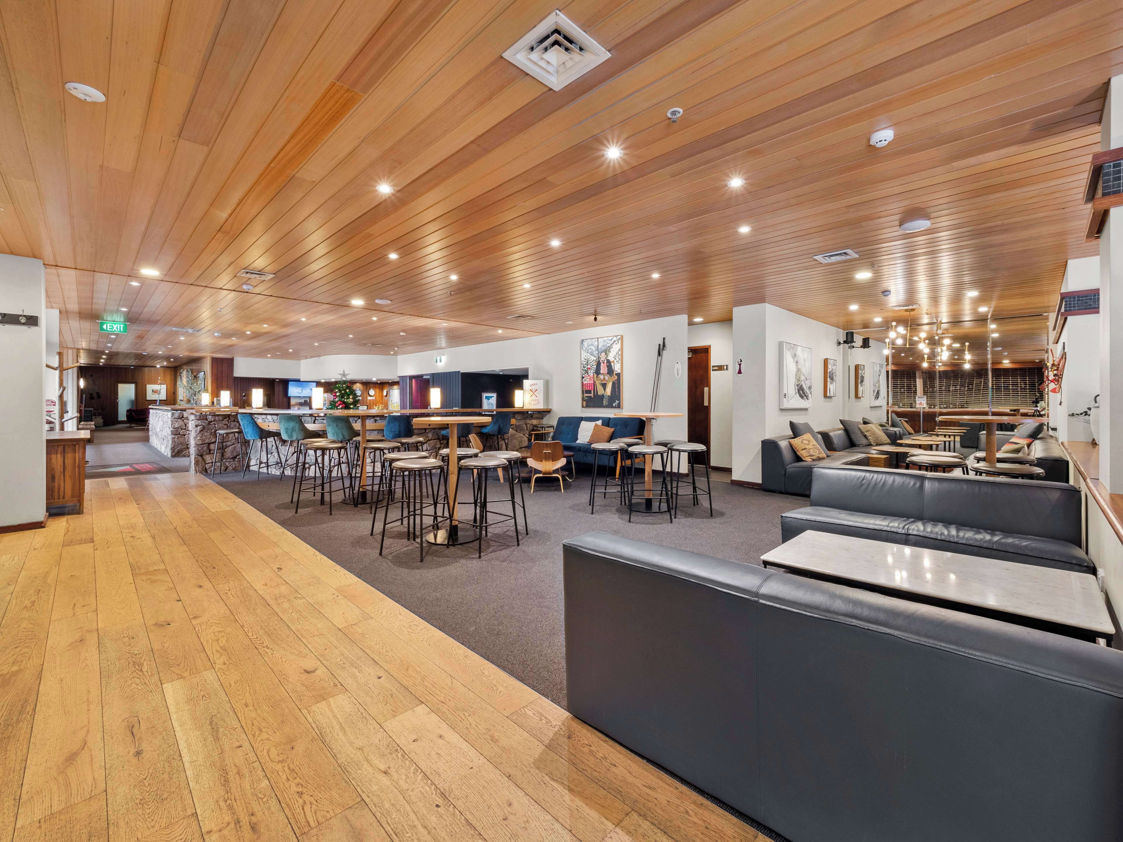 A spacious lobby with wooden flooring, a reception area, and seating arrangements including a sofa and tables.