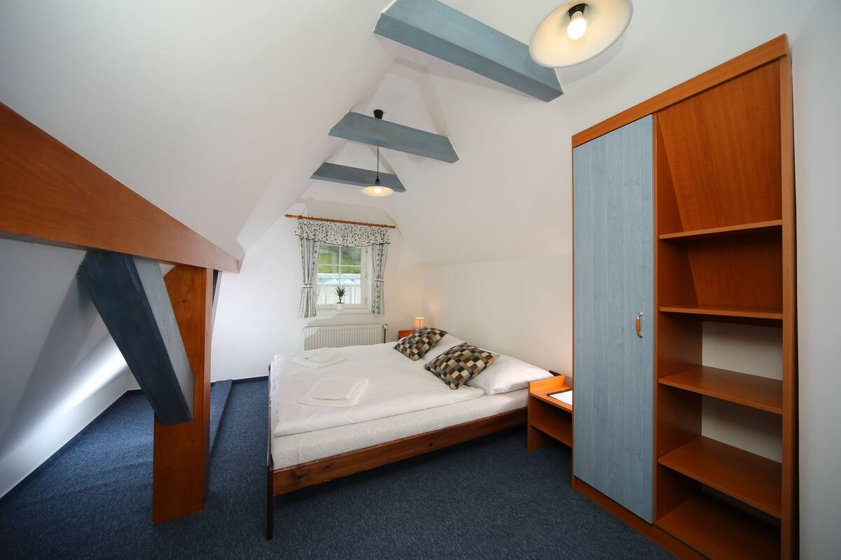 Een slaapkamer met een bed, een kledingkast, een raam met gordijnen en een plafondlamp.