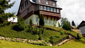 A multi-story house with a sloped roof, wooden exterior, and multiple windows. - Pension Seidl (Spindleruv Mlyn)