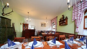 A dining area with wooden tables set for a meal, featuring blue napkins and wine glasses. - Pension Seidl (Spindleruv Mlyn)