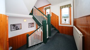 A wooden interior with a staircase, a radiator, and framed pictures on the walls. - Pension Seidl (Spindleruv Mlyn)