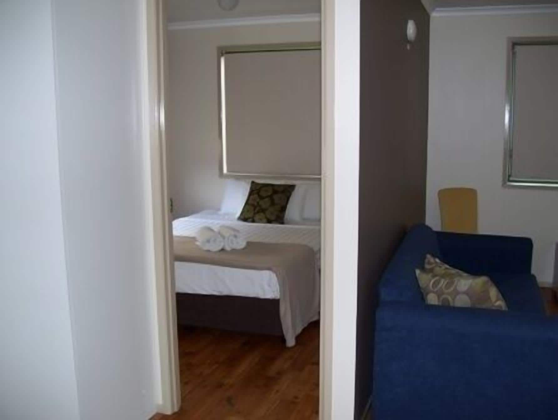 Un dormitorio con una cama, un sofá azul y una ventana.
