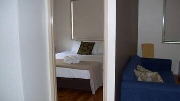 Une chambre à coucher avec un lit, un canapé bleu et une fenêtre.