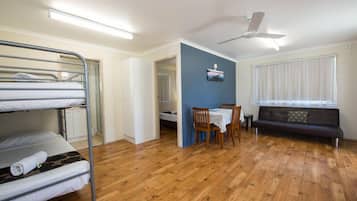 Una habitación con literas, una mesa de comedor con sillas, un sofá y un ventilador de techo.