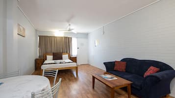 Une pièce comprenant un lit, un canapé bleu foncé, une table basse en bois et une petite table avec des chaises.