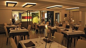 A restaurant with tables set for dining, featuring a modern interior with recessed lighting and a large floral decoration. - Heckenrose (Ringsheim)