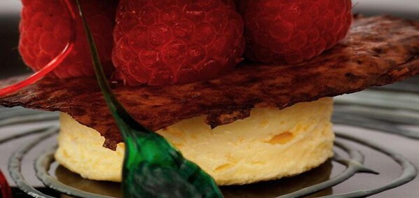 A dessert with a chocolate base and raspberries on top.