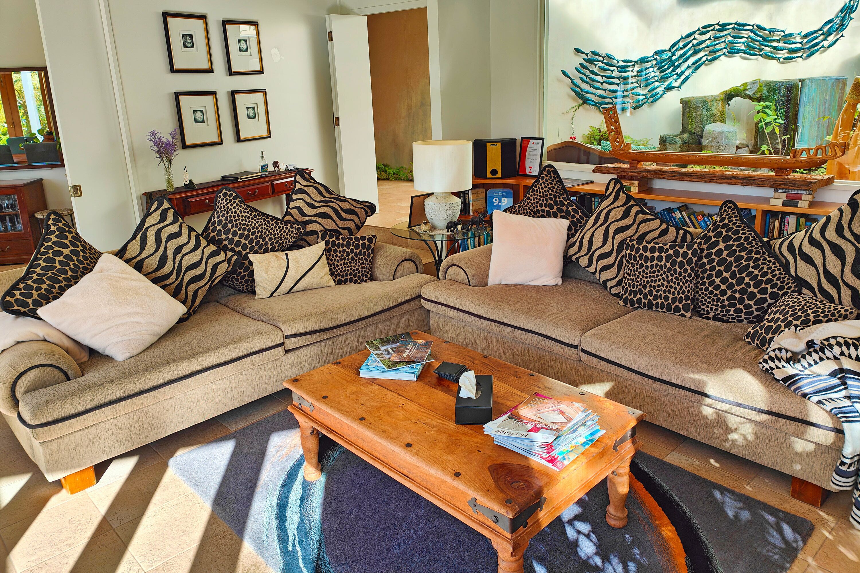 A living room with a sectional sofa, a wooden coffee table, and a decorative mirror.