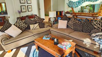 A living room with a sectional sofa, a wooden coffee table, and a decorative mirror.