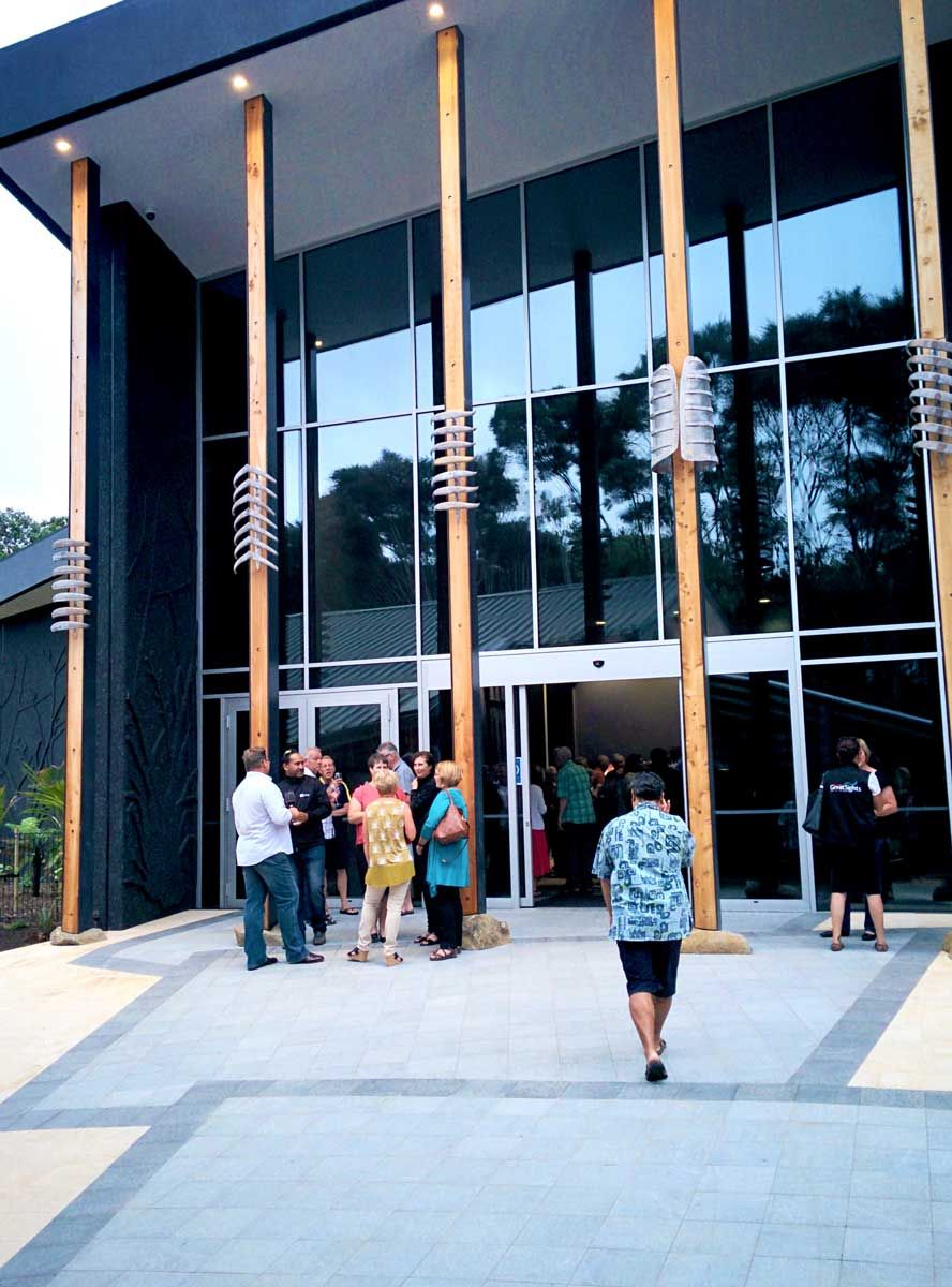 A modern building with large glass windows and wooden columns.