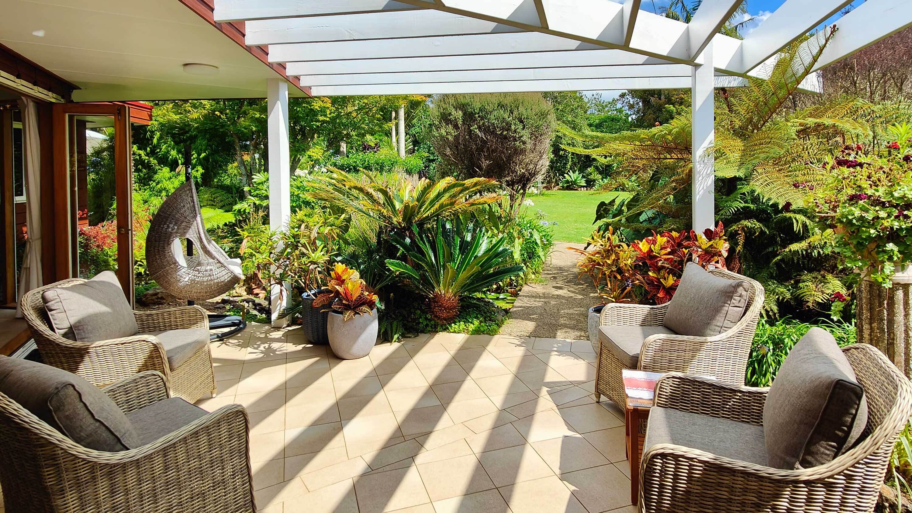 A covered patio with wicker furniture and potted plants.