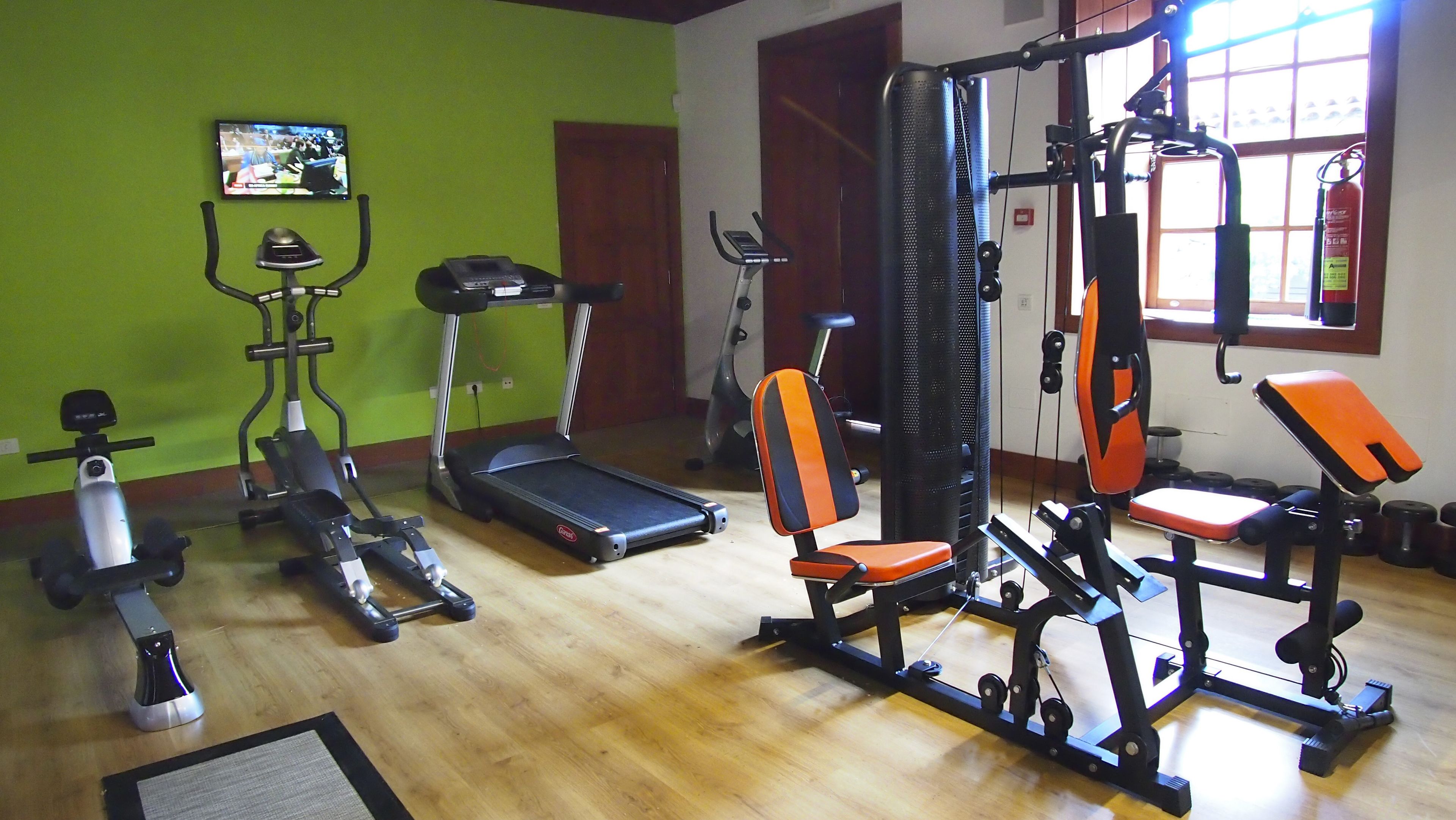 Une salle de sport équipée de divers appareils d’exercice, notamment des tapis de course, des appareils de musculation et un vélo d’appartement.