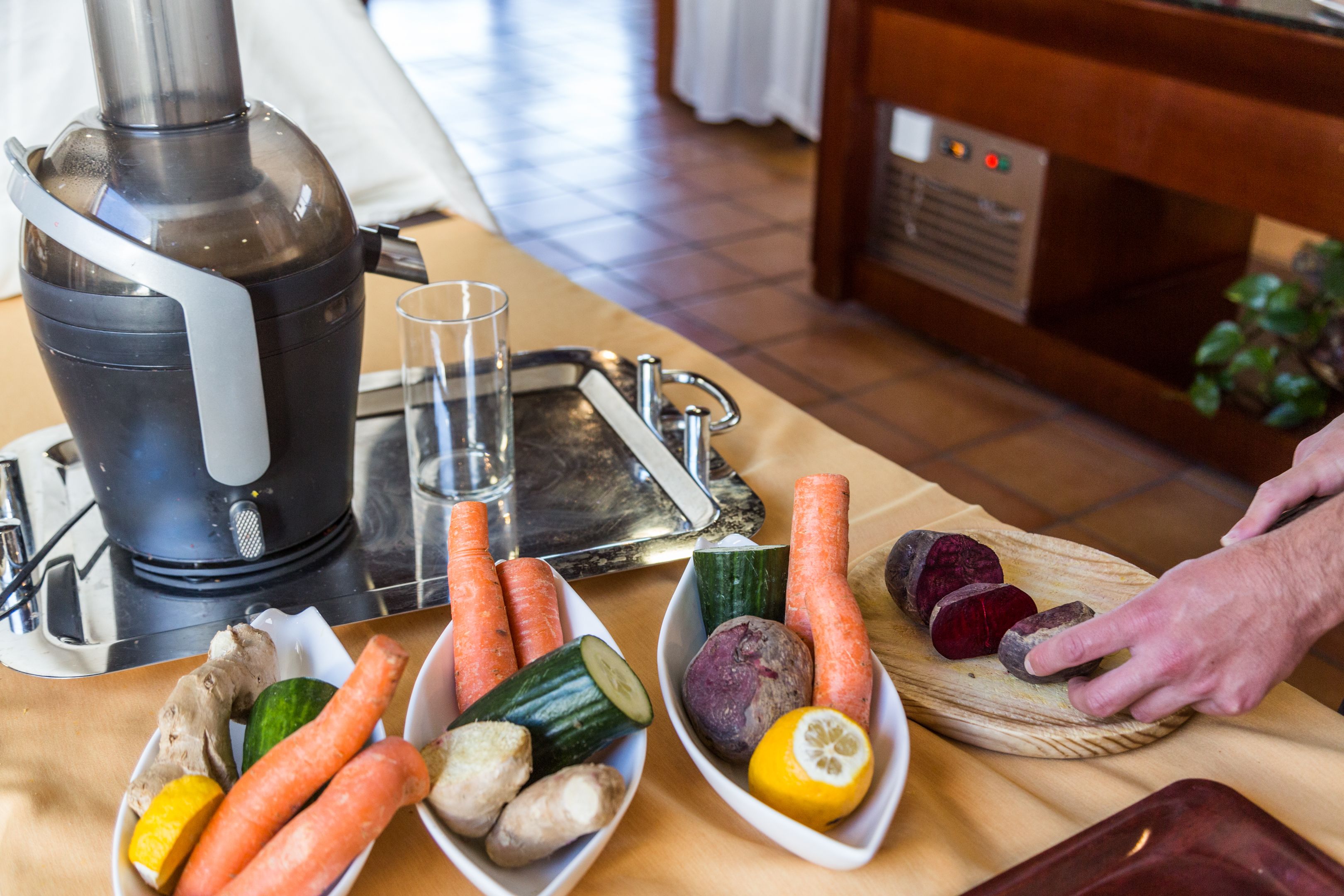 A kitchen with a juicer, vegetables, and a cutting board.