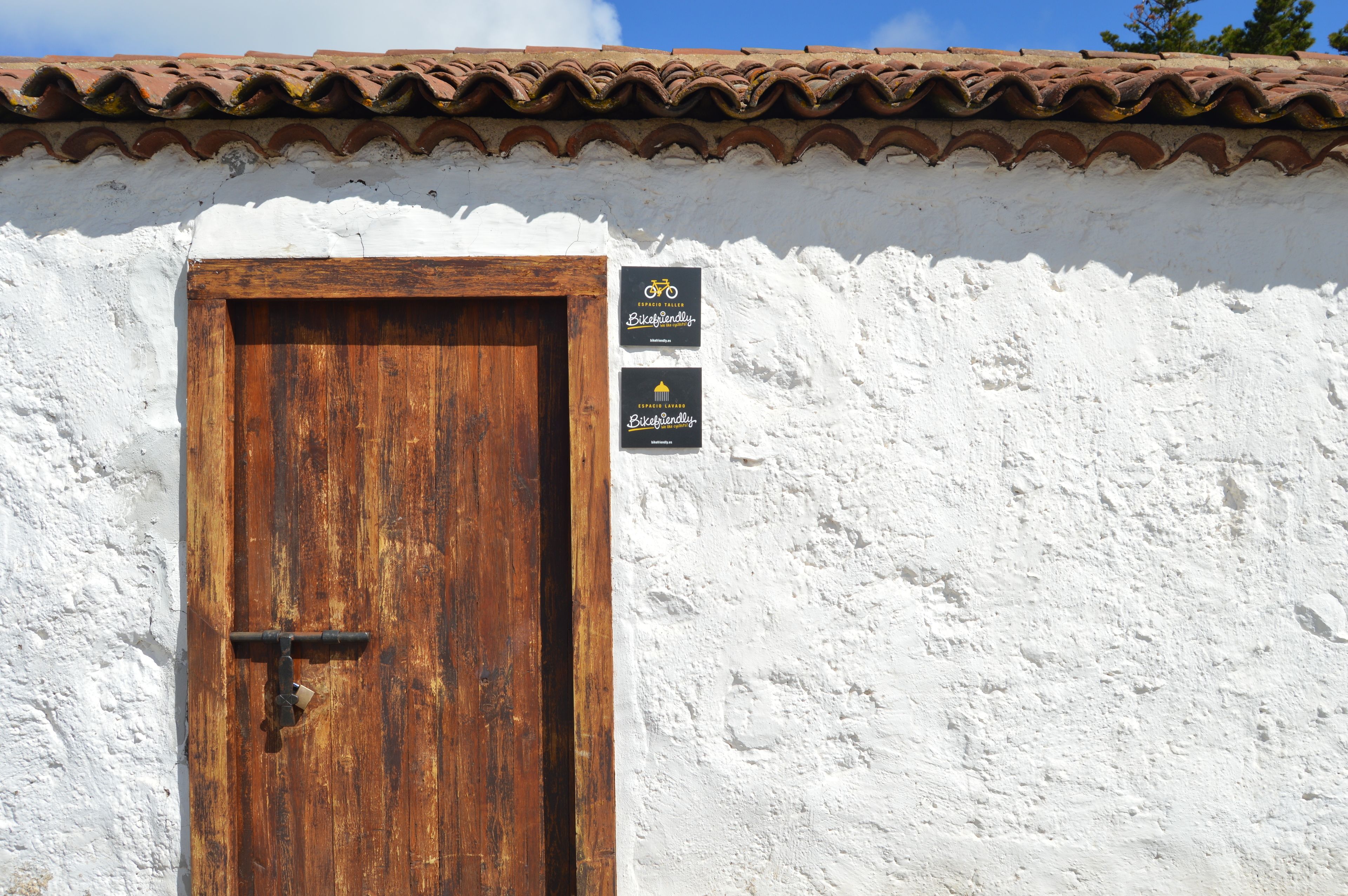 A rustic building with a wooden door and a white stucco wall.