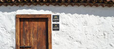 A rustic building with a wooden door and a white stucco wall.