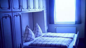 Quarto com duas camas, janela e radiador.