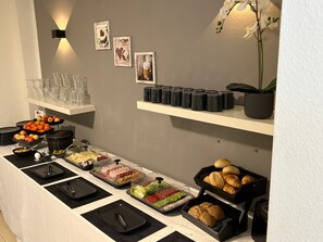 Un buffet proposant une variété de plats, de la vaisselle transparente et des tasses noires disposées sur des étagères.