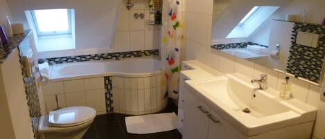 Un baño con bañera, inodoro, lavamanos y cortina de ducha.
