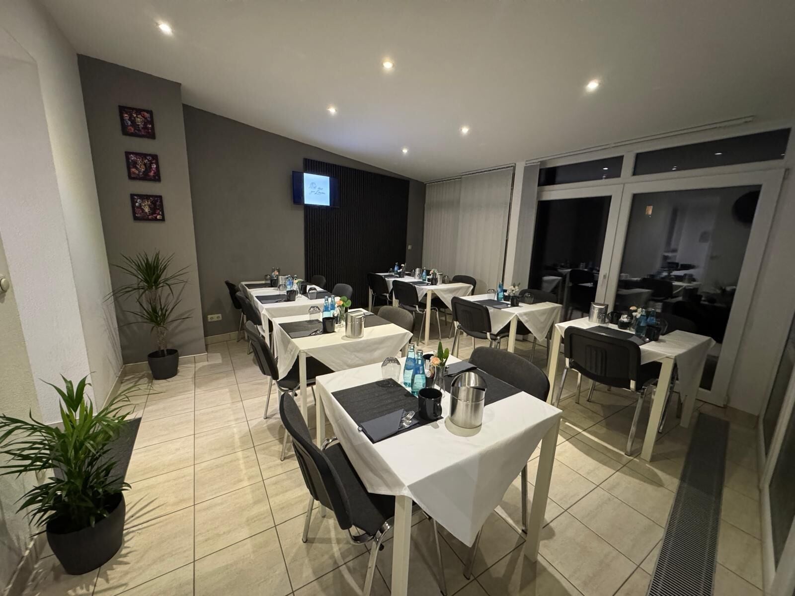 Un salón de conferencias de hotel con varias mesas, sillas y plantas en macetas.