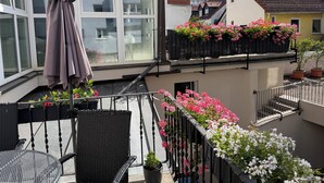 A balcony with wicker furniture, potted plants, and a view of neighboring buildings. - Hotel Zum Löwen (Bad Homburg v.d. Hoehe)