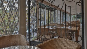 A covered outdoor seating area with wicker furniture and metal railings. - Le Suisse Elegance Hotel (Campos do Jordão)