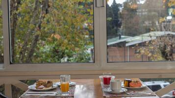A table with breakfast items and a view of trees through a window.