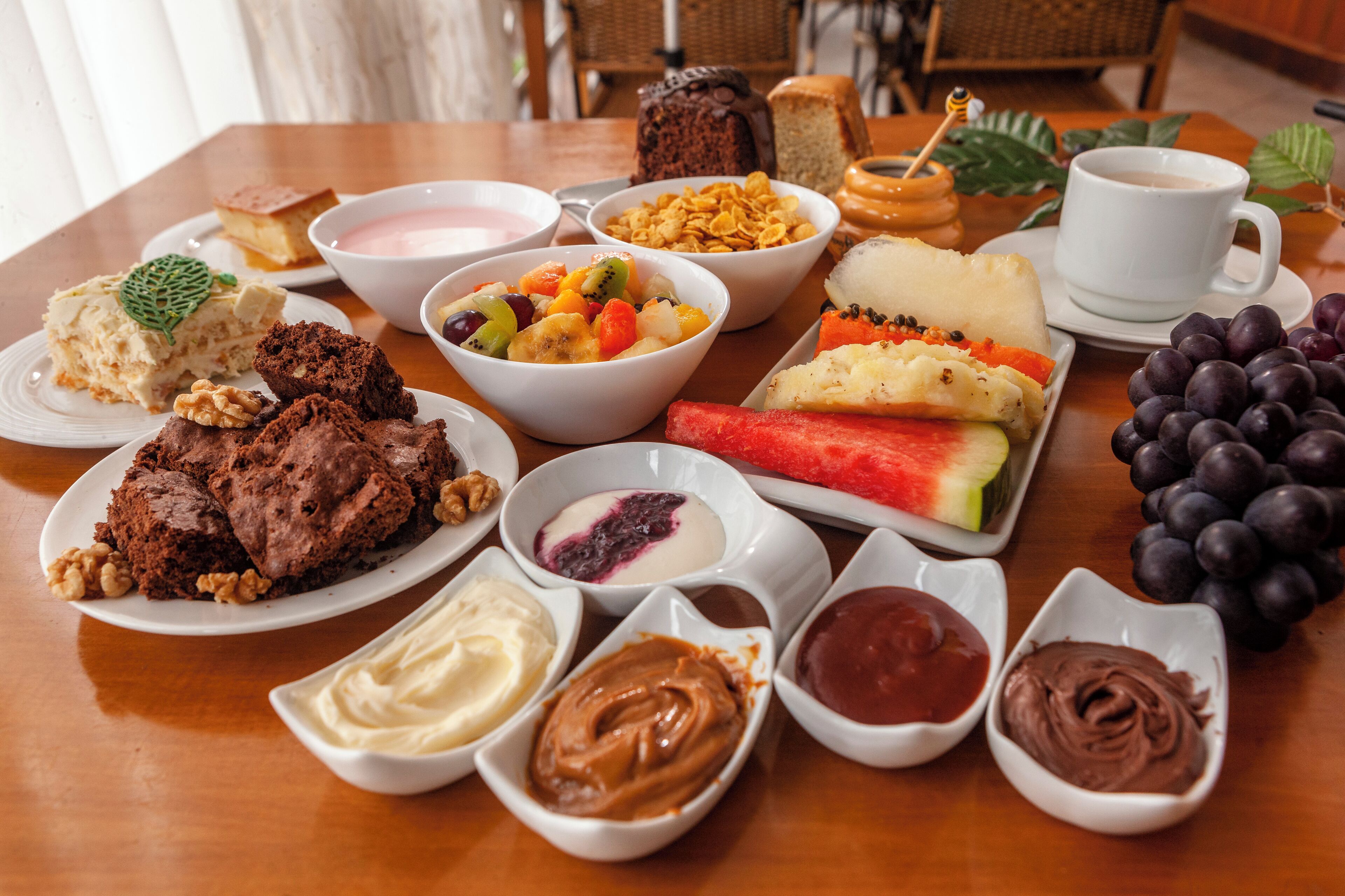 A variety of breakfast items including pastries, fruits, and condiments on a wooden table.