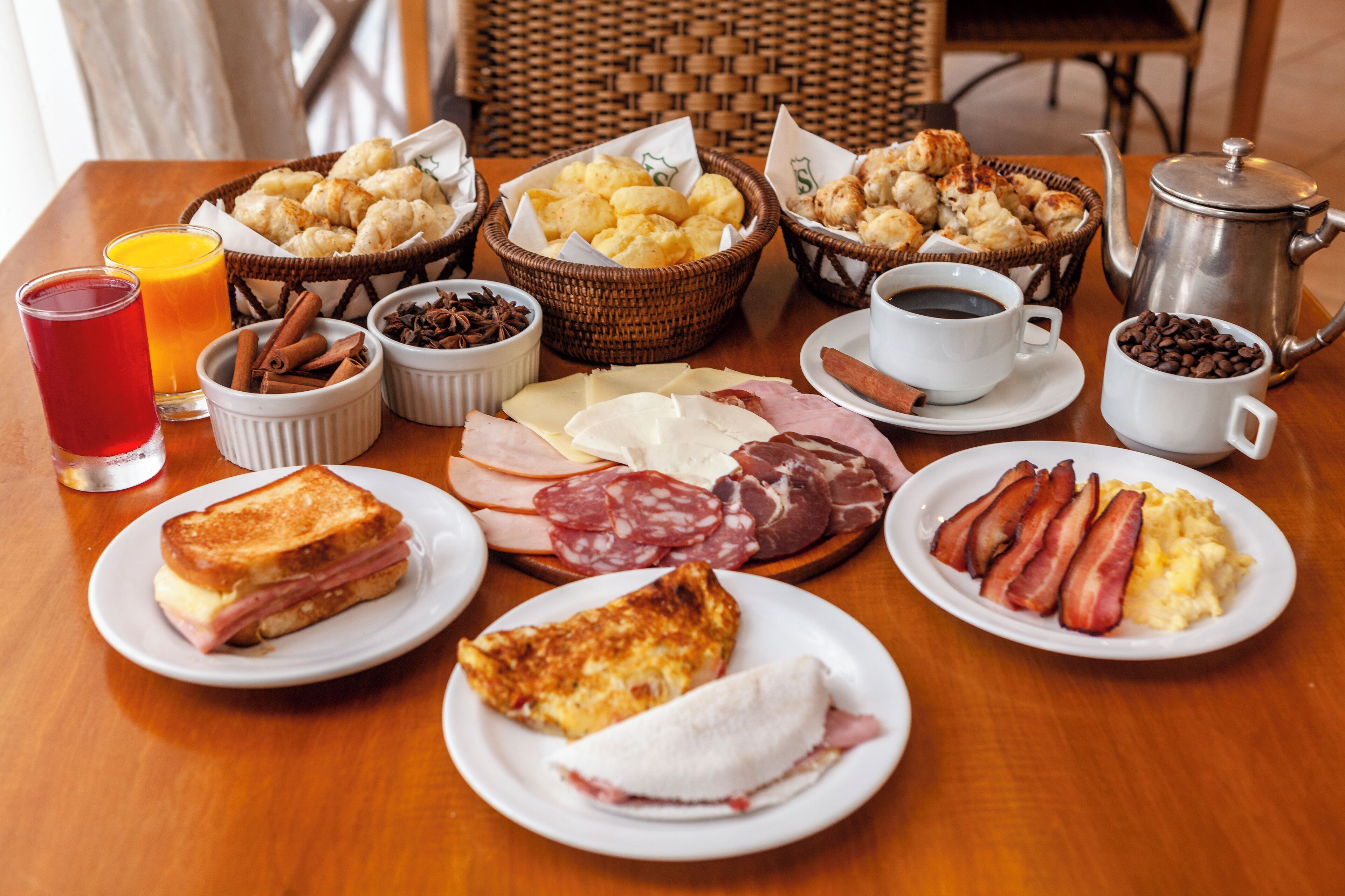 A breakfast table with various food items, including toast, eggs, bacon, and pastries.
