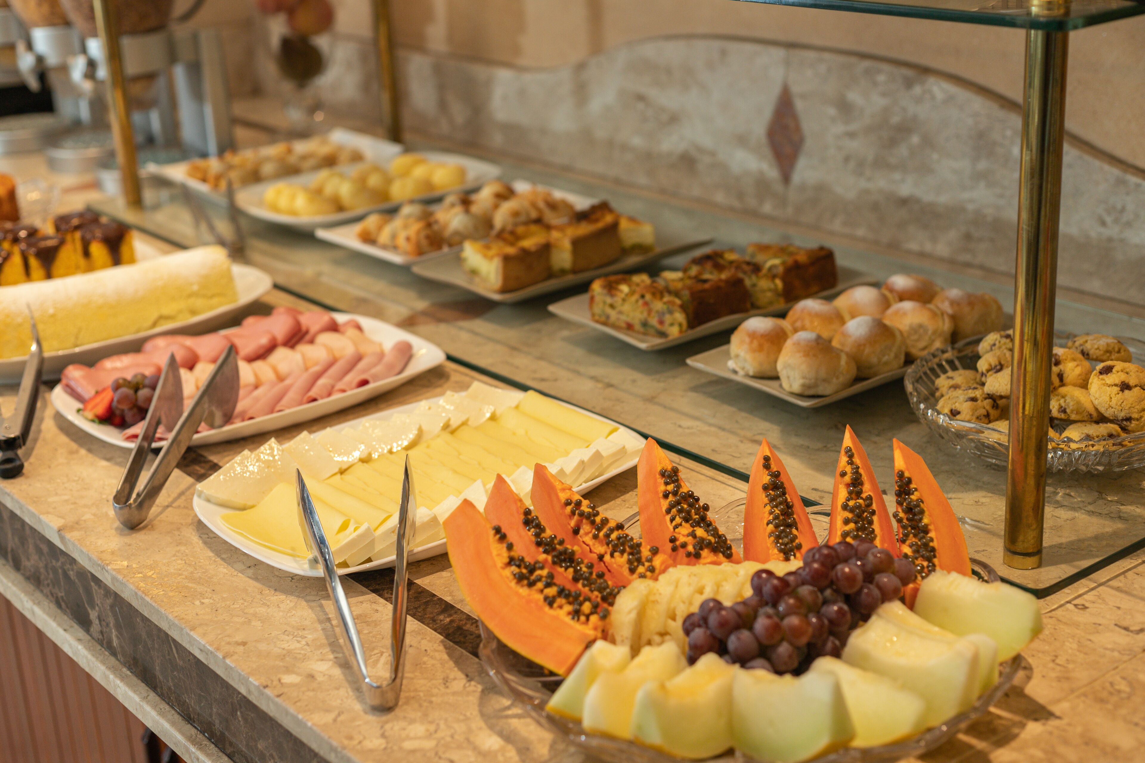 A buffet with various food items including fruits, cheeses, and pastries.