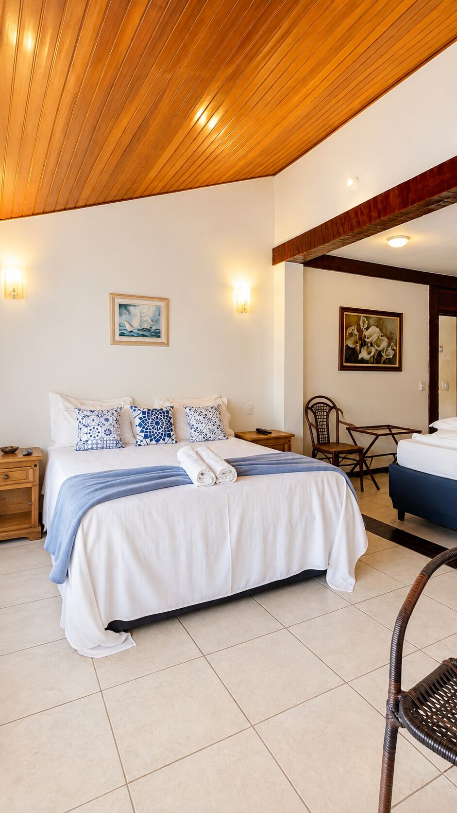 A bedroom with a bed, bedside tables, a chair, a desk, and a painting on the wall.