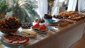 A buffet with various dishes including fruits, pastries, and desserts. - Coronado Beach (Búzios)