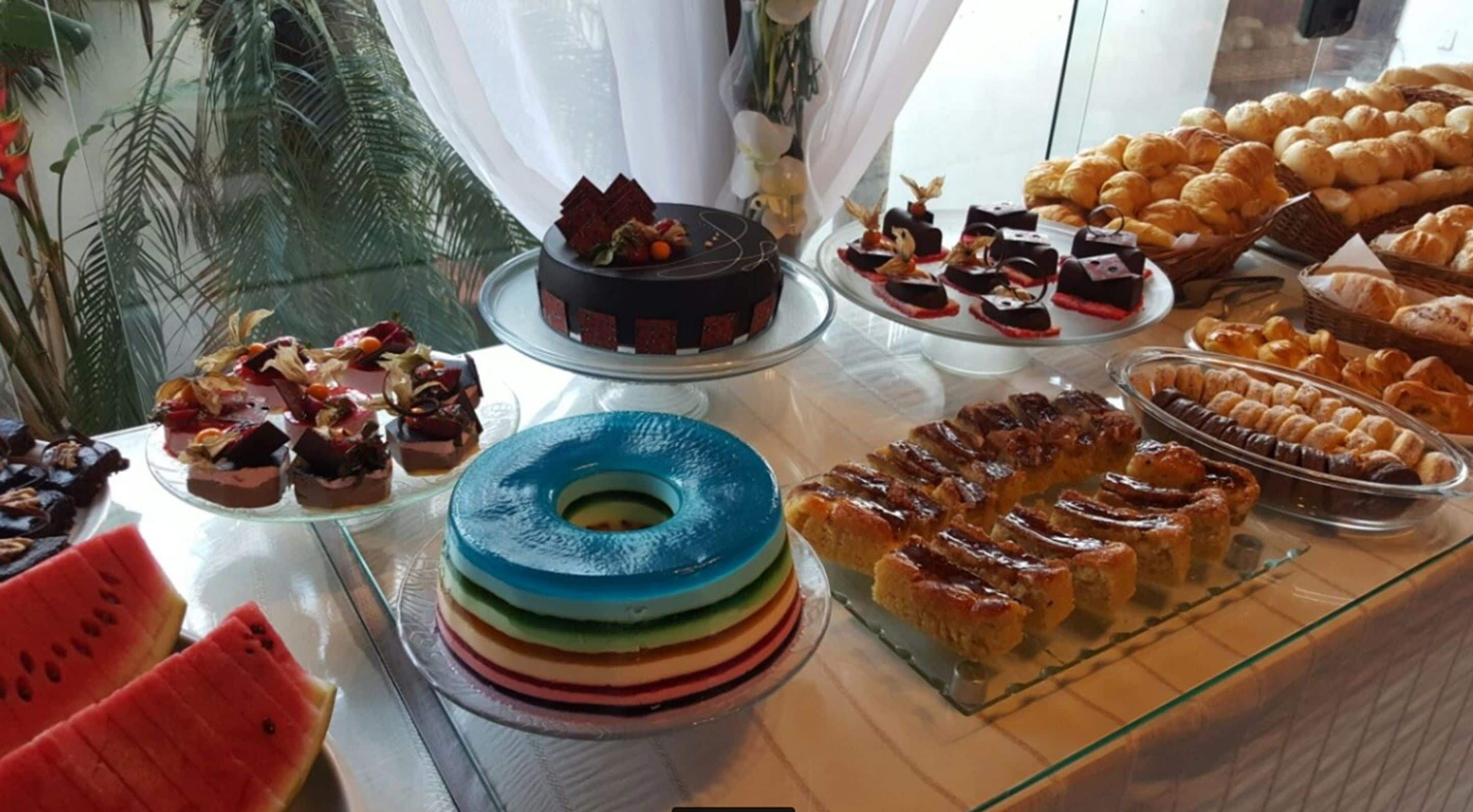Un bufé con diversos postres, incluyendo un pastel de varias capas, pastelería y fruta.