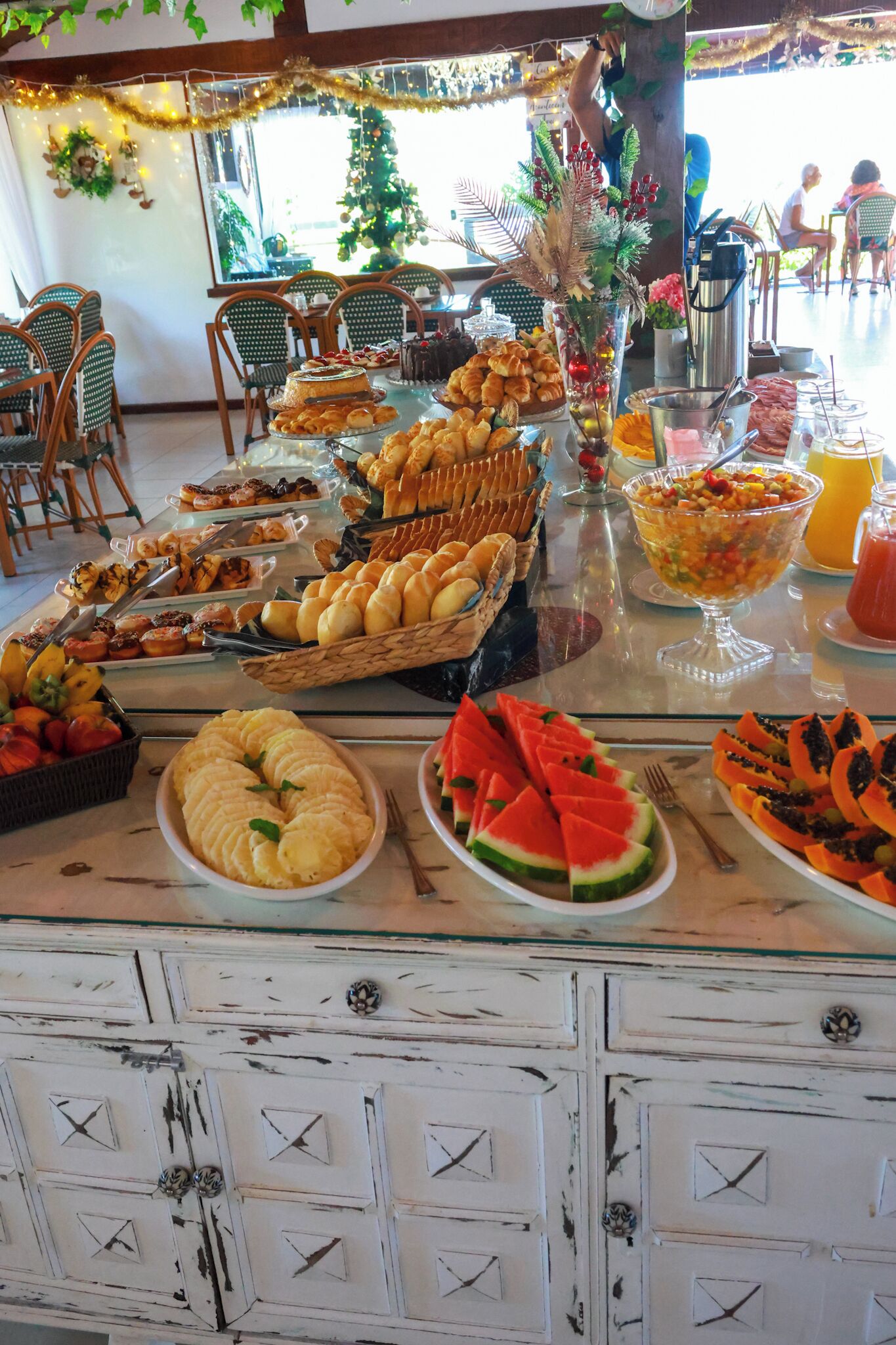 Mesa de buffet com diversos alimentos e uma árvore decorativa.