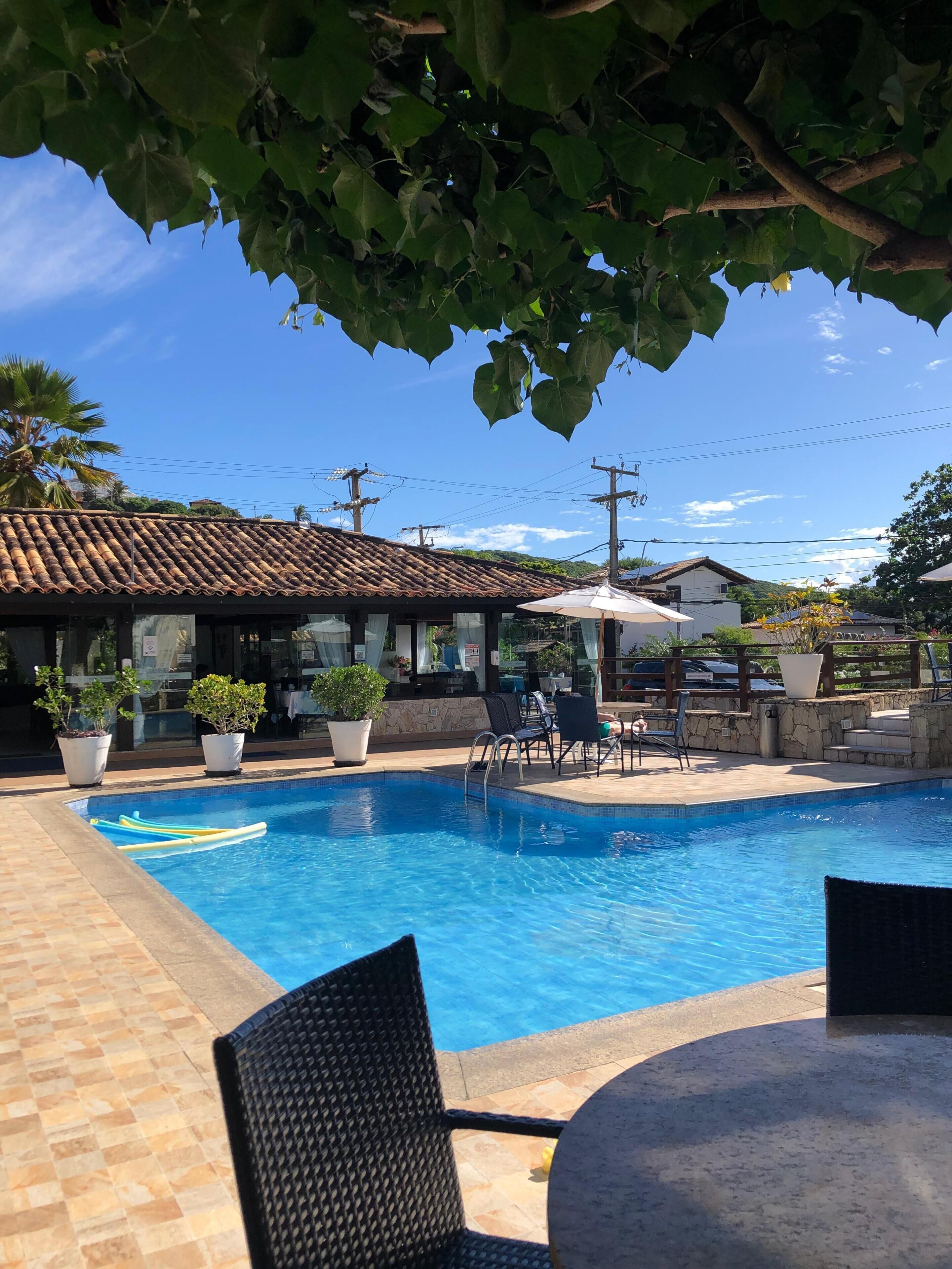 A swimming pool with lounge chairs and potted plants, surrounded by buildings with tiled roofs.