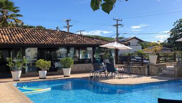 A swimming pool with lounge chairs and potted plants, surrounded by buildings with tiled roofs.