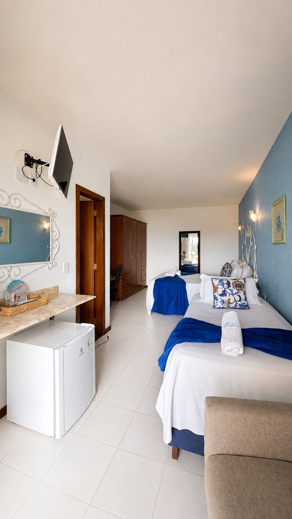 Une chambre d’hôtel équipée d’un lit, d’un bureau, d’un réfrigérateur et d’une télévision.