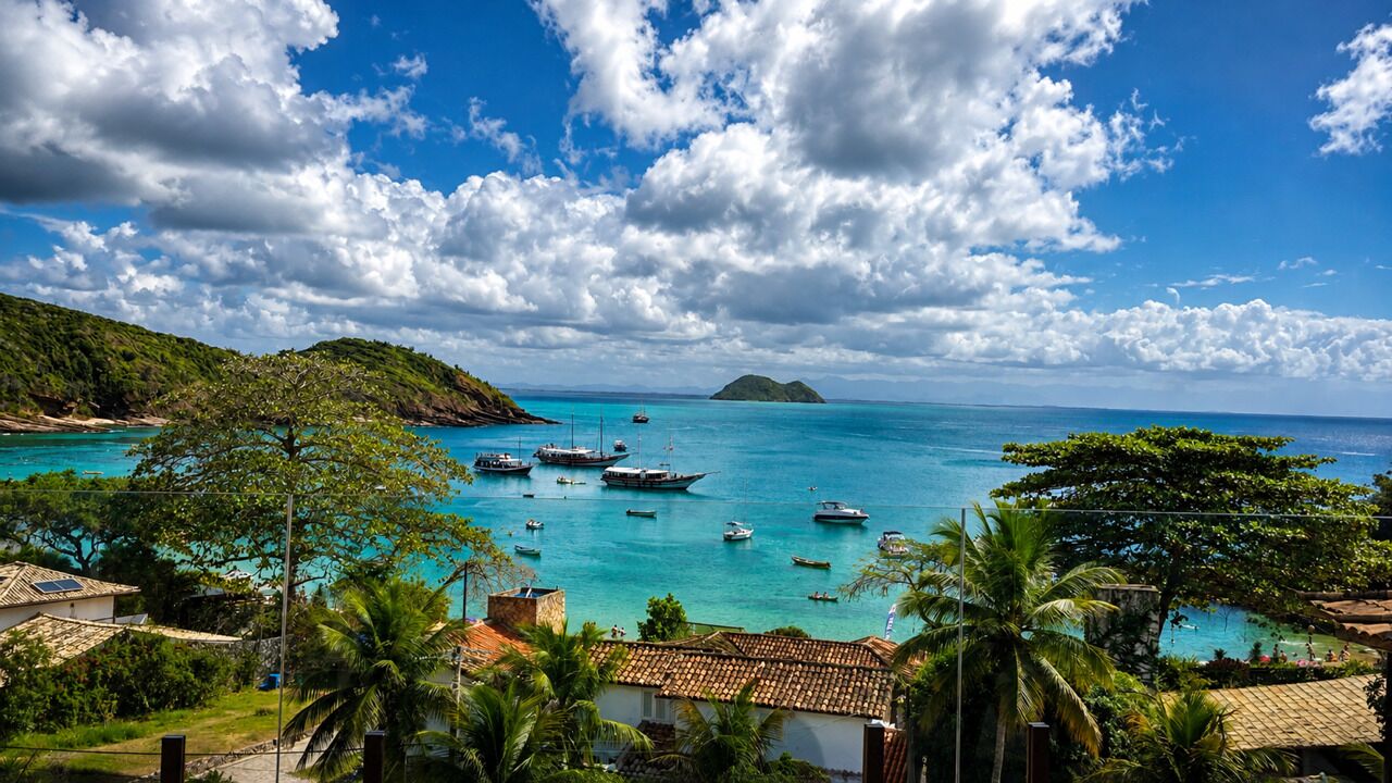 Vista costera con barcos, una zona para nadar y una colina con vegetación.