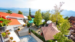 A courtyard with outdoor seating, a stone wall, and a view of distant mountains. - Hotel Bellevue (Kranj)