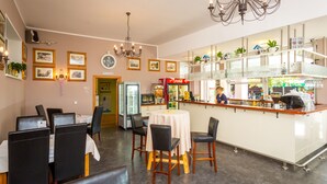 A restaurant with a bar area, dining tables, chairs, and a refrigerator. - Hotel Bellevue (Kranj)
