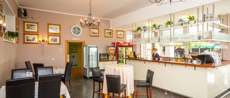 A restaurant with a bar area, dining tables, chairs, and a refrigerator.