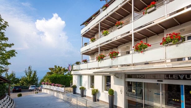 A multi-story hotel with balconies adorned with potted plants and flowers. - Hotel Bellevue (Kranj)